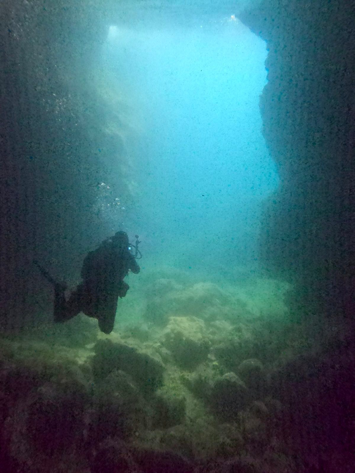 A diver swimming through a cave
